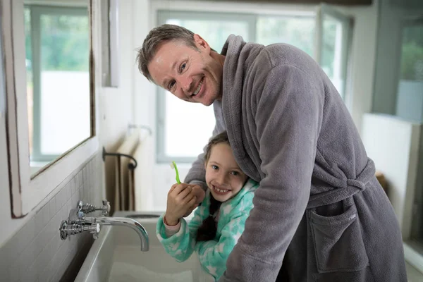 Padre e hija sosteniendo cepillo de dientes en el baño —  Fotos de Stock