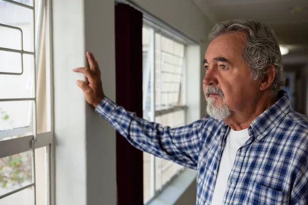 Homme âgé réfléchi regardant par la fenêtre — Photo