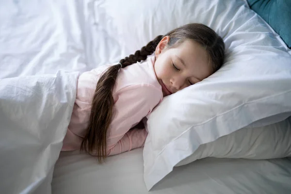Chica durmiendo en la cama en el dormitorio — Foto de Stock
