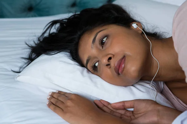 Doordachte vrouw luisteren naar muziek op bed — Stockfoto