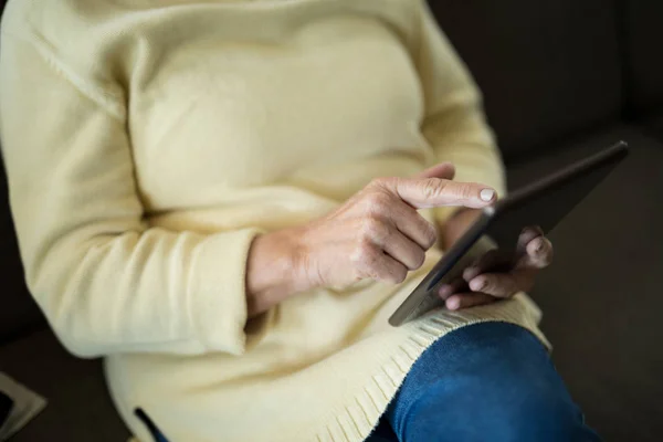 Ανώτερος γυναίκα χρησιμοποιώντας tablet στον καναπέ — Φωτογραφία Αρχείου