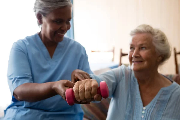 Infirmière aidant femme âgée à soulever haltère — Photo