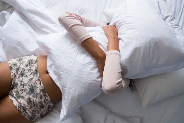 Mulher segurando travesseiro na cama — Fotografia de Stock
