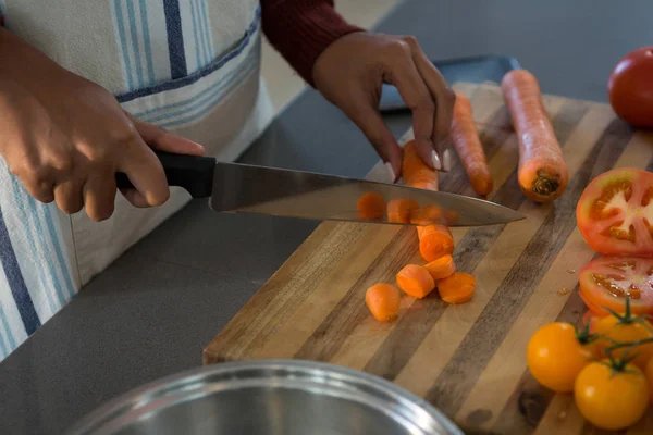 Жінка ріже моркву на кухні — стокове фото