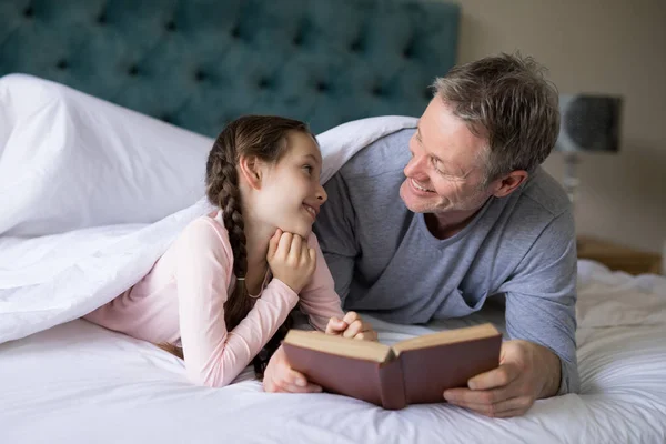 Pai e filha lendo livro na cama — Fotografia de Stock