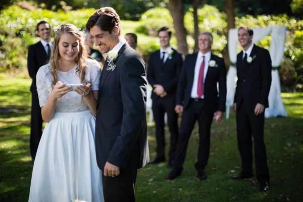 Bruid en bruidegom herziening van foto's op telefoon — Stockfoto