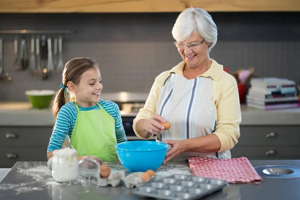 Grandmother showing granddaughter to break eggs — Stock Photo, Image