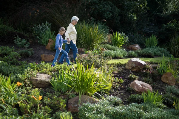 Babička a vnučka chůzi v zahradě — Stock fotografie