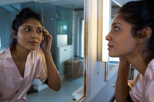Kobieta, zastanawiając się nad lustrem w łazience — Zdjęcie stockowe