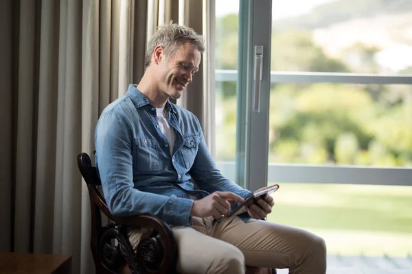 Улыбающийся человек с помощью планшета на стуле — стоковое фото
