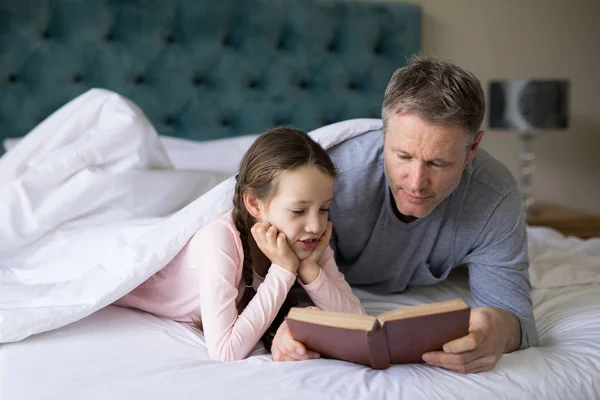Father and daughter reading book on bed — Stock Photo, Image