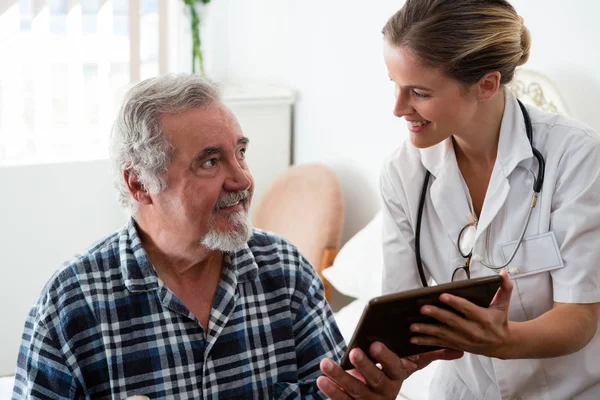 Dokter weergegeven: tablet aan man in bejaardentehuis — Stockfoto