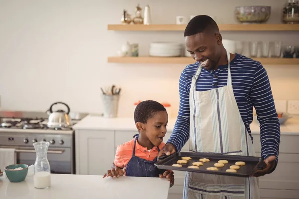Padre sosteniendo bandeja mientras hijo mirando galletas —  Fotos de Stock