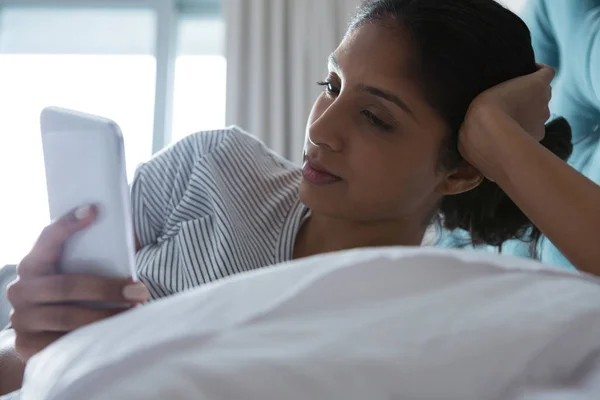 Kvinna med telefonen medan de vilar på sängen — Stockfoto