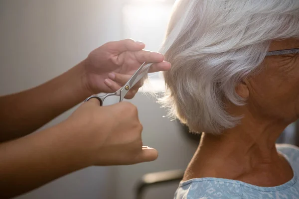 Las manos del esteticista cortando el cabello de la mujer mayor — Foto de Stock