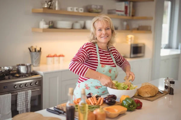 Senior Kvinna blandning grönsaker sallad — Stockfoto