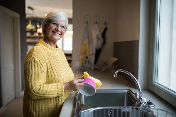 Femme âgée lave-vaisselle dans l'évier de cuisine — Photo