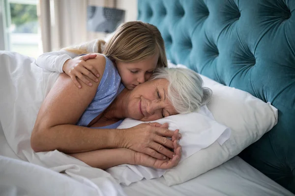 Granddaughter kissing her grandmother on bed — Stock Photo, Image