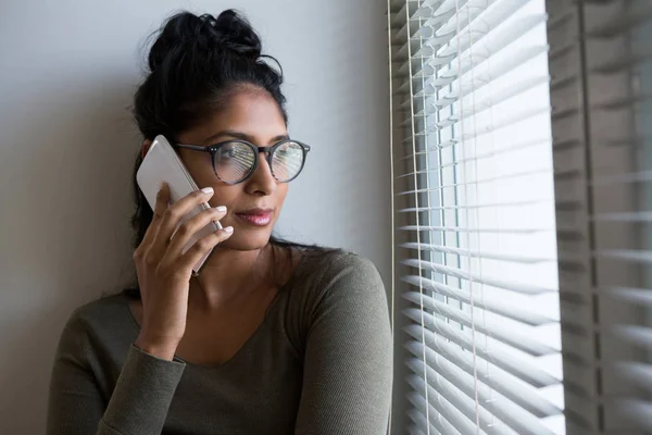 Женщина, говорящая по телефону через окно — стоковое фото