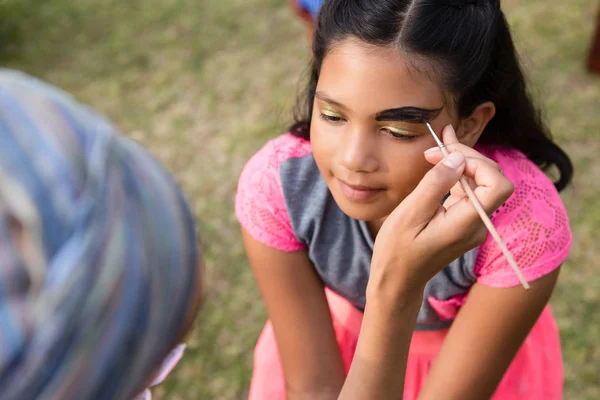 Woman doing face paint on girl — Stock Photo, Image