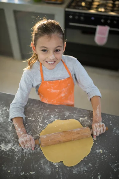 Маленькая девочка сглаживает тесто — стоковое фото