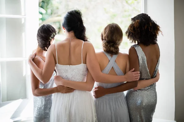 Noiva e damas de honra de pé juntos perto da janela — Fotografia de Stock