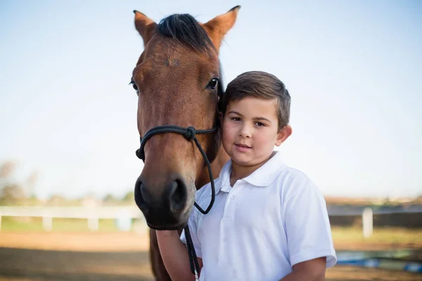 Хлопчик вершника пестить коня на ранчо — стокове фото