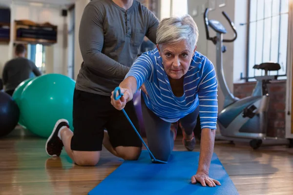 Fisioterapeuta auxiliando a mulher idosa no exercício — Fotografia de Stock