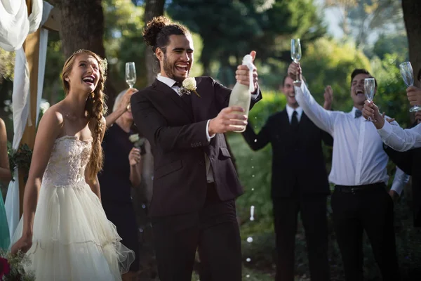 Apertura dello sposo bottiglia di champagne al parco — Foto Stock