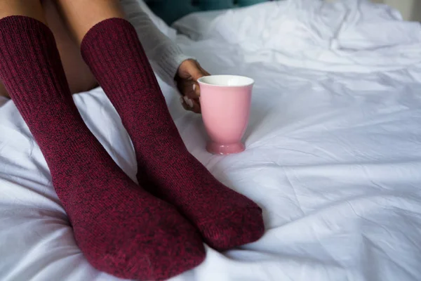 Γυναίκα με κούπα καφέ στο κρεβάτι — Φωτογραφία Αρχείου