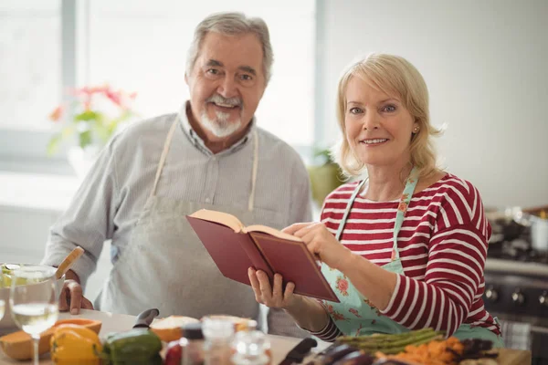 Pareja mayor con libro de recetas en la cocina —  Fotos de Stock