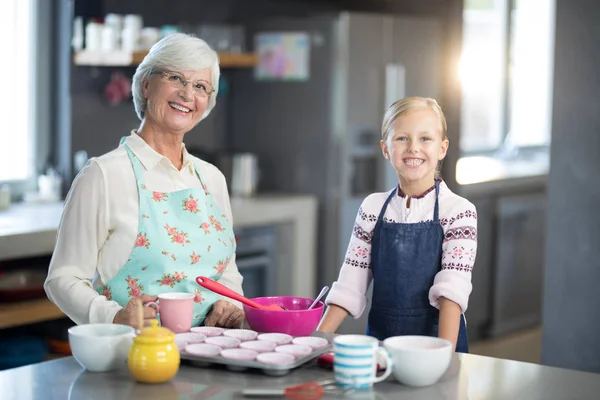 Granddaughter and grandmother standing in kitchen — Stock Photo, Image