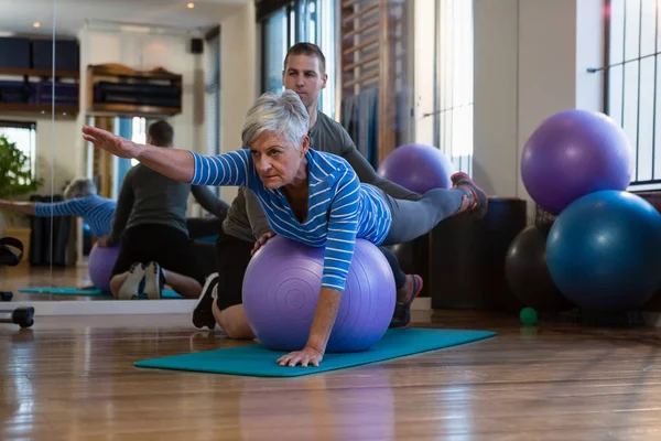 Fisioterapeuta que ayuda a la mujer mayor en la realización de ejercicio — Foto de Stock