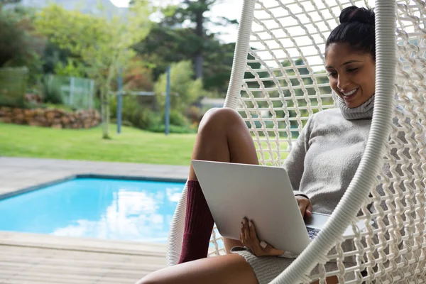 Mulher sorridente usando laptop no balanço — Fotografia de Stock