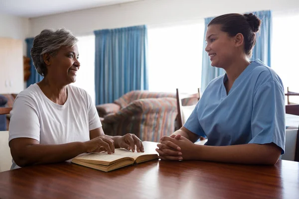 Pielęgniarka, rozmowy przy stole starszy Kobieta — Zdjęcie stockowe