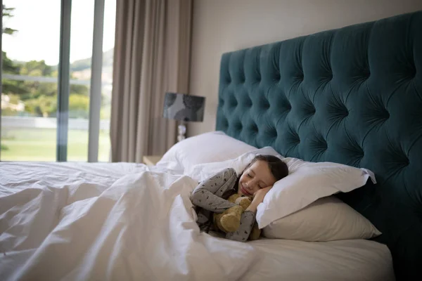 Дівчина спить на ліжку з плюшевим ведмедем — стокове фото
