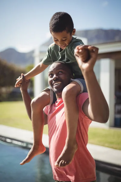 Батько, що носить сина на плечах біля басейну — стокове фото