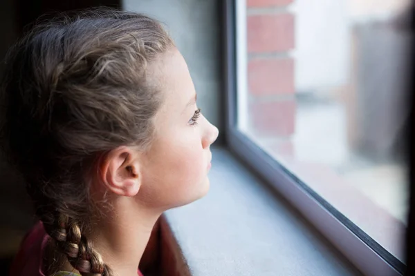 Ragazza adolescente riflessivo guardando attraverso la finestra — Foto Stock