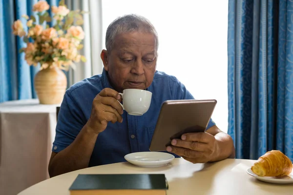 Uomo anziano che utilizza tablet digitale a tavola — Foto Stock