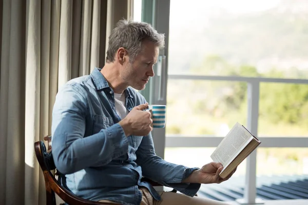 Человек, читающий книгу за чашкой кофе — стоковое фото