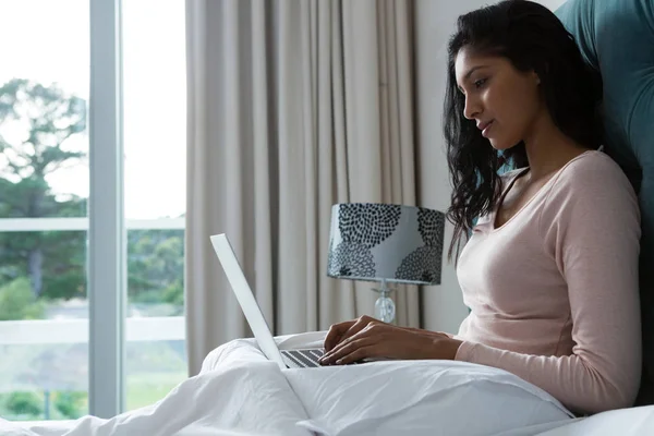 Jovem mulher usando laptop na cama — Fotografia de Stock