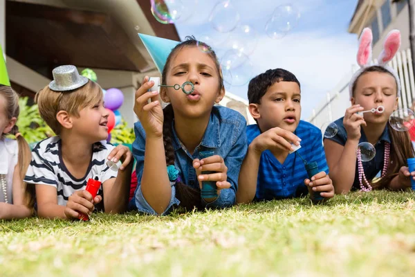 Kinderen bellen blazen terwijl liggend op veld — Stockfoto