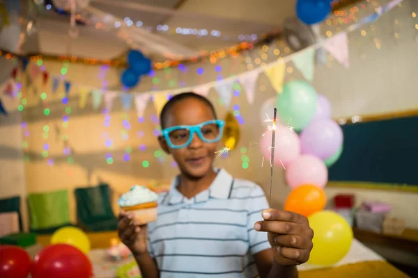 Chico sosteniendo sparkler y cupcake — Foto de Stock