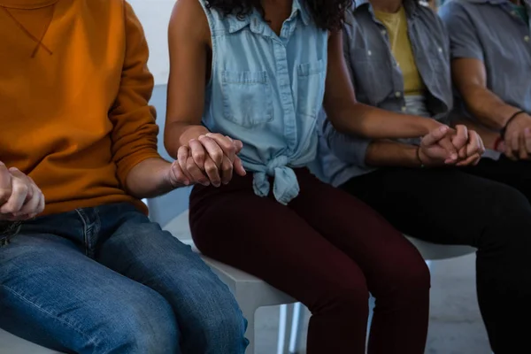 Freunde halten Händchen auf Stühlen — Stockfoto