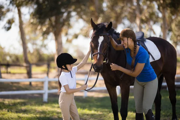 Žokej dívka a žena hladí koně — Stock fotografie