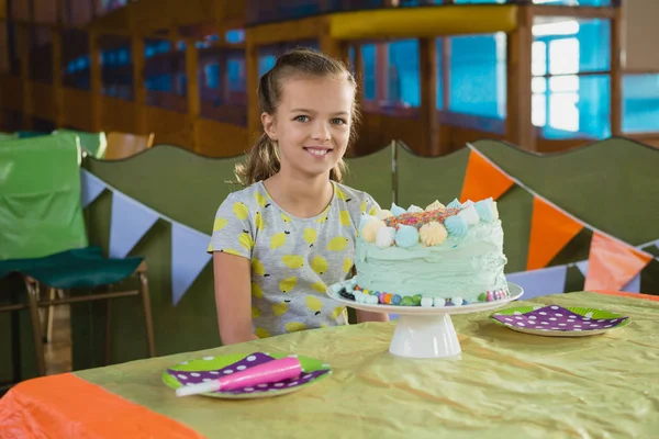 Chica sentada cerca de pastel de cumpleaños — Foto de Stock