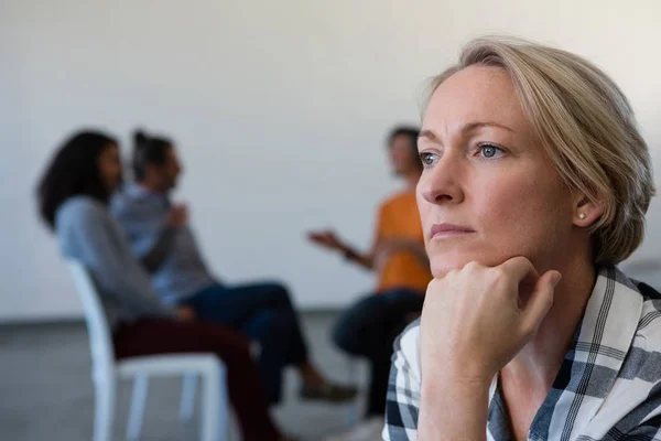 Kvinna sitter med handen på hakan — Stockfoto