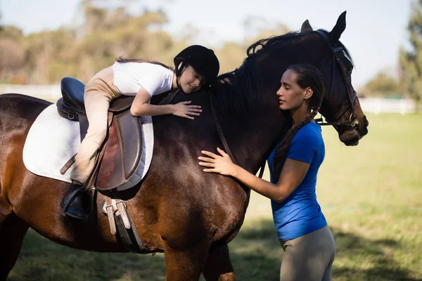 Jockey femenino y chica abrazando caballo — Foto de Stock