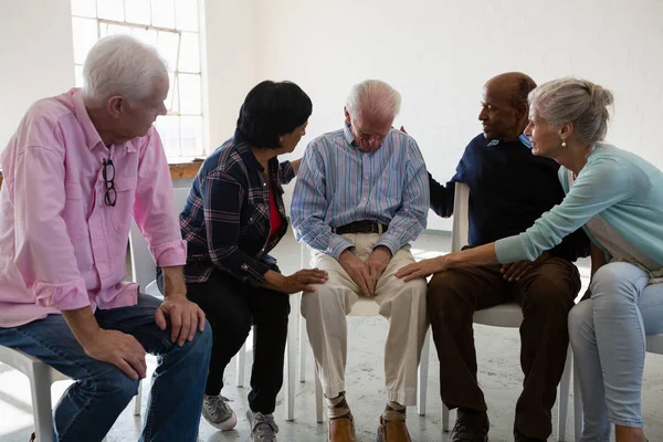 Senior friends consoling male friend