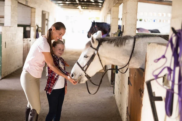 Smiling sisters feeding horse